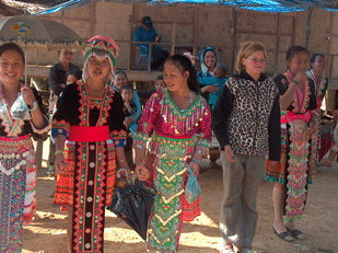 hmongmeisjes/>Tegen 
de middag stoppen we bij Nong Khiauw, een plaatsje 
aan de rivier Ou. ’s Middags zullen we met de boot verder reizen; hier nemen we 
afscheid van onze bus en van de chauffeur – we hebben steeds prima gereden! 
Eerst nog tijd om wat te eten. Er zijn wat winkeltjes en restaurantjes; wij 
picknicken langs de rivier.</p>
<p>We gaan met twee slowboats (die ook nog best snel varen), 
en hebben zo goed zicht op mensen die zichzelf of hun kleding staan te wassen in 
de rivier; er wordt gevist met netten of met viskorven, en vaak worden we vanaf 
de kant enthousiast gegroet.</p>
<p>Een paar keer zien we ook een zelfgebouwde 
waterkrachtcentrales: aan een paar palen midden in de rivier hangt een 
generator, waarmee door de stroming elektriciteit wordt opgewekt.</p>
<p>Er zijn wat stroomversellingen, her en der steken rotsen 
boven het water uit – de schipper moet goed opletten!</p>
<p>Bij het dorpje van de Tai Lu waar we zullen overnachten, 
worden we ontvangen met tromgeroffel: tussen de akkertjes op de schuine 
rivierhelling zien we een jongetje enthousiast roffelen op wat potten en pannen. 
Het dorpshoofd komt ons verwelkomen, en dan krijgen we allemaal een mooie 
bloemenslinger om. De grote bagage blijft op de boot; we hebben alleen een klein 
rugzakje bij ons – die brengen we eerst naar een van de twee stenen huizen waar 
we vannacht zullen slapen. Dan lopen we naar voetbalveld. Daarvoor moeten we een 
asfaltweg oversteken – het dorp is dus niet alleen over de rivier te bereiken. 
De kinderen spelen ‘takro’, een soort voetvolleybal met een rotan bal, zoals we 
dat ook in Thailand gezien hebben. Bij de Aziatische Spelen was Thailand 
kampioen takro geworden. Emiel heeft duidelijk de meeste voetbalervaring, de 
anderen hebben er meer moeite mee om de bal goed te raken. Litty speelt als 
enige meisje ook lang mee – takro wordt ook door meisjes gespeeld, maar hier 
doen alleen Laotiaanse jongens mee. Naast het takro-veld spelen de kinderen ook 
voetbal. </p>
<p>Naast het sportveld is een wat. In een kale ruimte, waarvan 
de grond vol ligt met stapels betondraad, probeert een zestal monniken hun 
aandacht bij de Boeddhateksten te houden; het ziet er niet aantrekkelijk uit om 
hier monnik te zijn. </p>
<p>Als het gaat schemeren, lopen we terug naar de huizen waar 
we zullen eten en slapen. Litty en Johan gaan nog even door met takro, die 
hebben de smaak te pakken. Ze komen ons toch vrij snel achterna – iemand had een 
gong geluid, en onmiddellijk waren alle kinderen gestopt met spelen en renden ze 
weg.</p>
<p>
<img class=